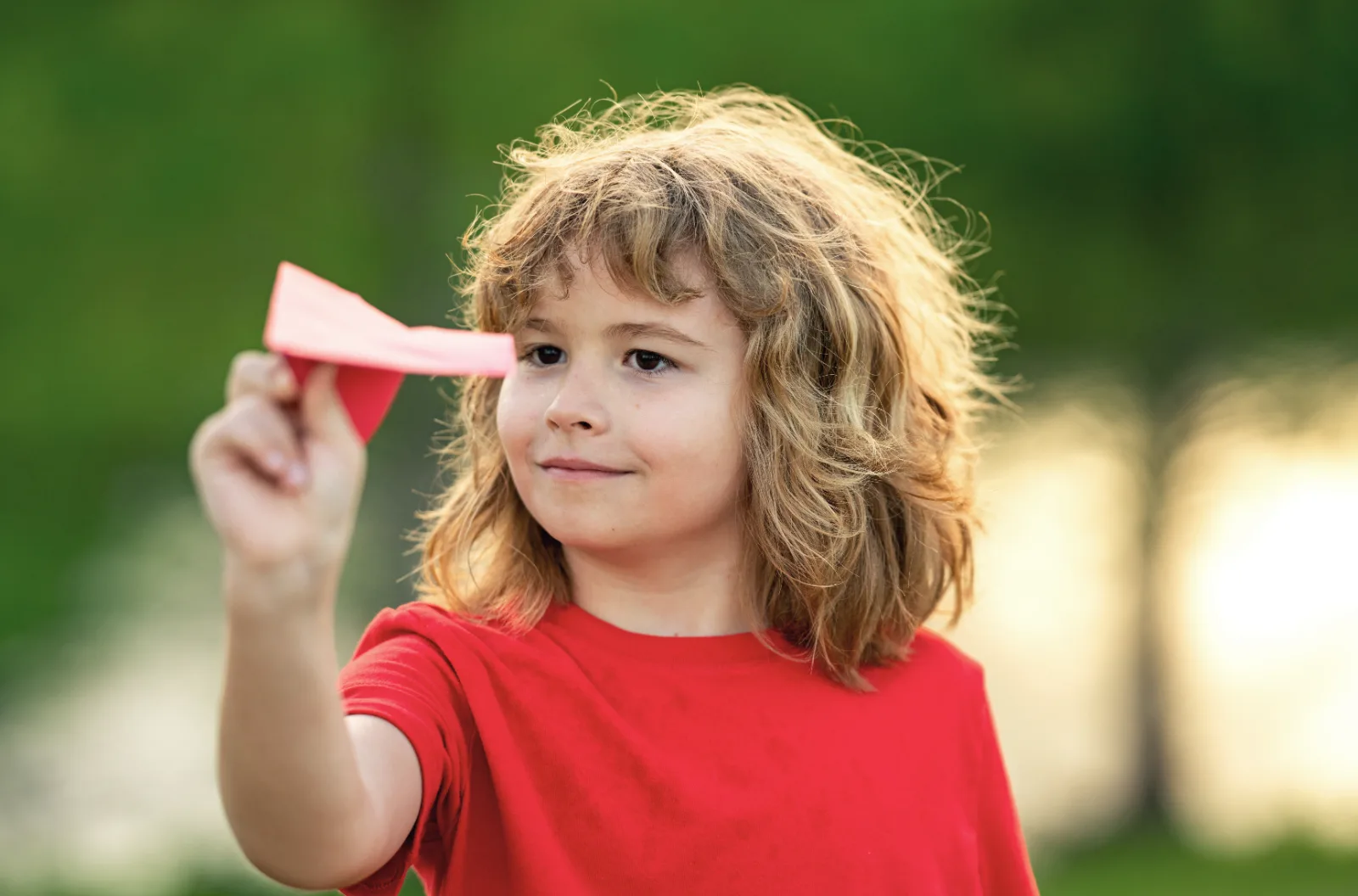 Child launching a paper airplane in the park